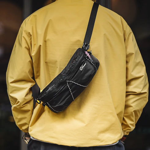 Person wearing a yellow jacket with a black waist bag on a blurred background